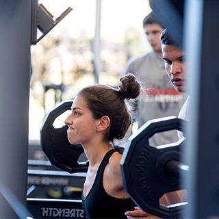 Girl lifting weights at TCU rec center